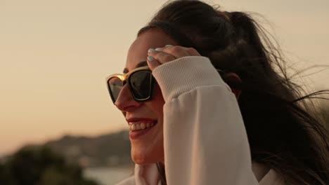 disparo en cámara lenta de una mujer atractiva con gafas de sol viendo el atardecer