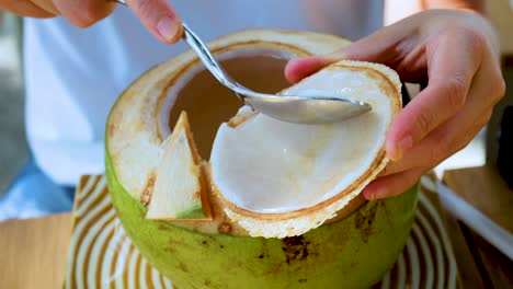 hands scooping coconut meat with a spoon