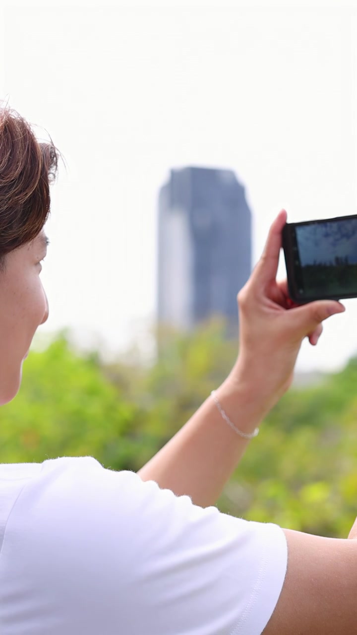 Jovem tirando fotos com smartphone e usando smartwatch ao ar livre
