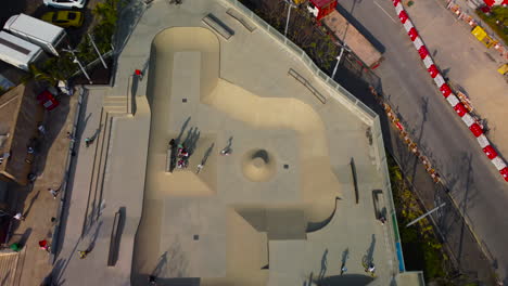 tilting dolly push in drone bird view over skate park. 4k ariel footage showing bmx rider skater hong kong, revealing construction site behind.