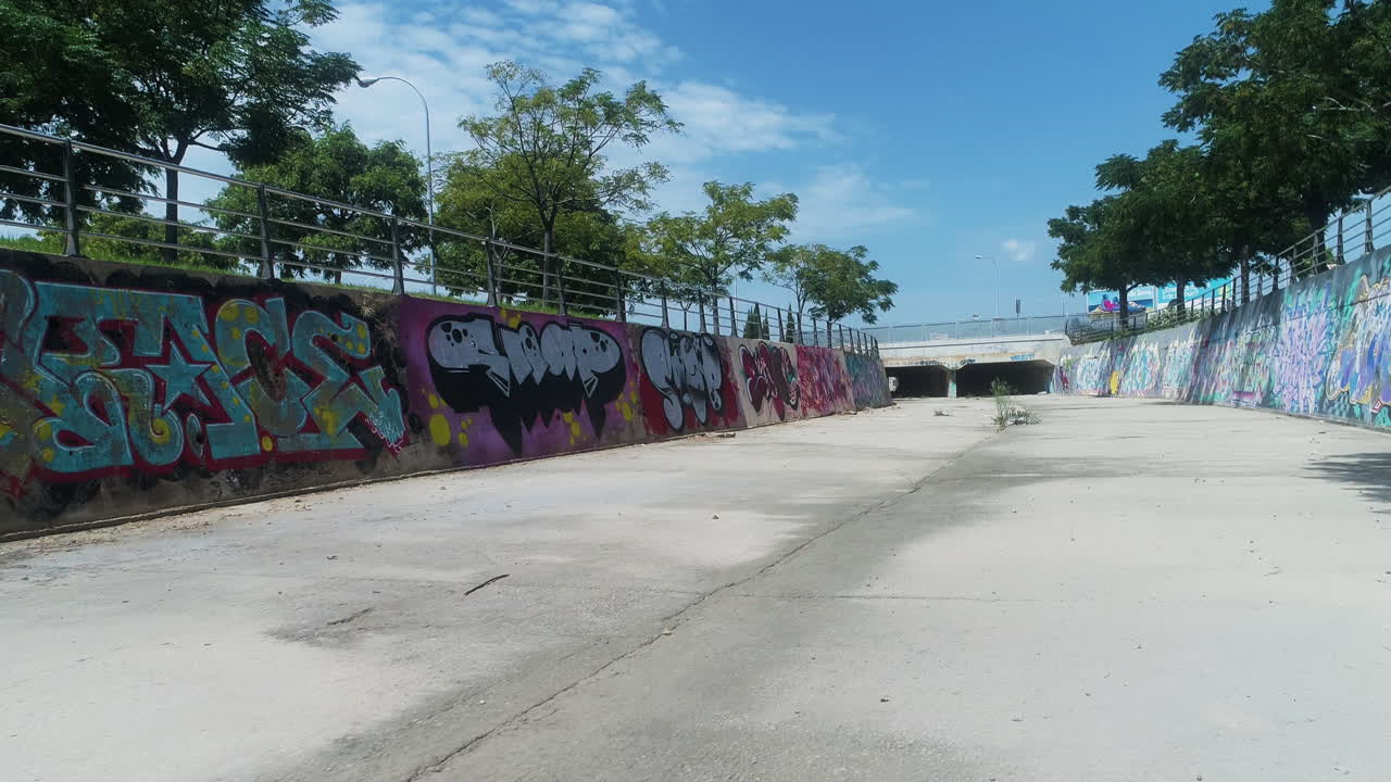 Drone avanza lungo una strada di cemento ricoperta di graffiti