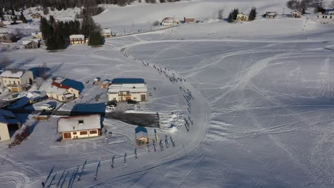 Pueblo-De-Lajoux-Sobrevuelo-Aéreo-Con-Casas-Cubiertas-De-Nieve-Junto-A-La-Carrera-De-Esquí-De-Biatlón-Durante-La-Luz-Del-Sol-En-Invierno