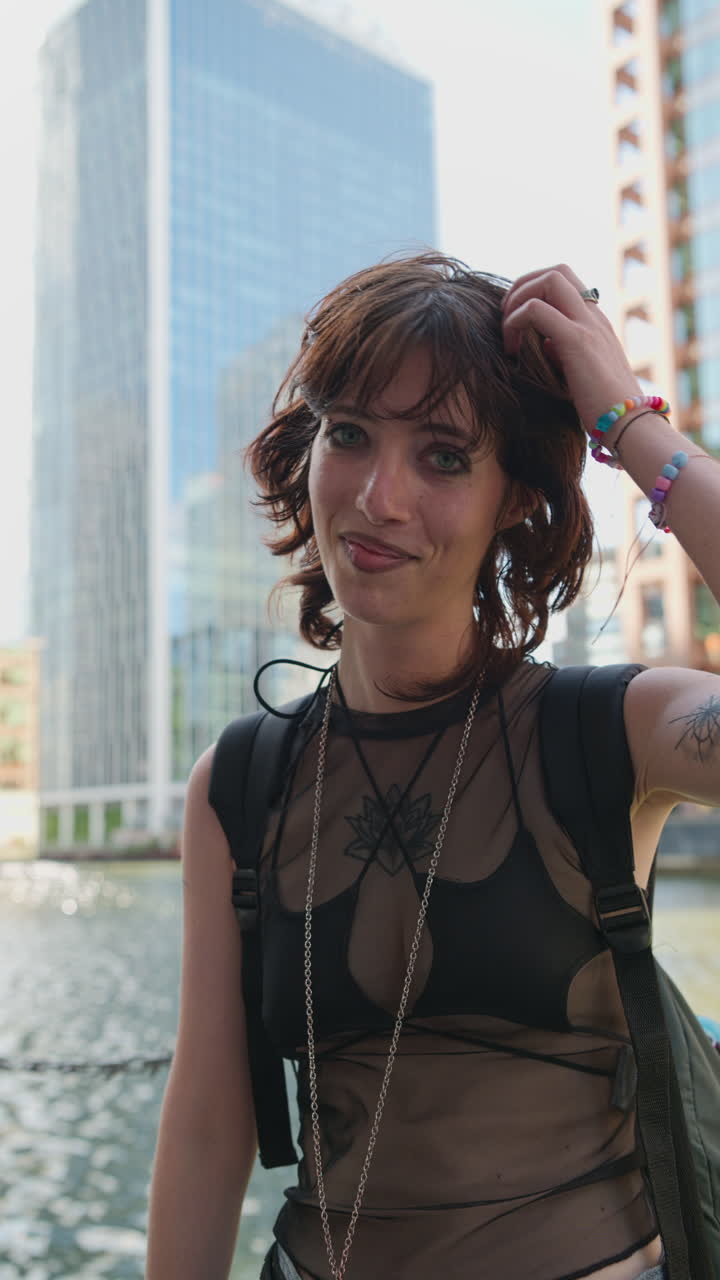 retrato vertical de moda al aire libre de una mujer joven de estilo alternativo con tatuajes y perforaciones en canary wharf en los muelles de londres filmado en tiempo real 3