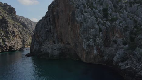 Drohne-Fliegt-An-Einem-Sonnigen-Tag-über-Türkisfarbenes-Wasser-In-Sa-Calobra,-Mallorca,-Spanien-In-Richtung-Torrent-De-Pareis