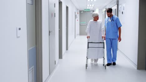 Male-nurse-assisting-senior-patient-in-using-a-walking-frame
