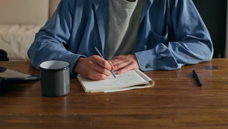 person writing in a notebook at a table