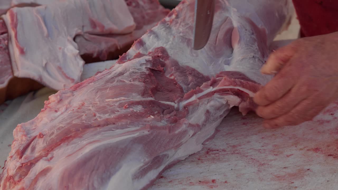 Knife cuts pork fat on table during north Portugal butchering in Minho region