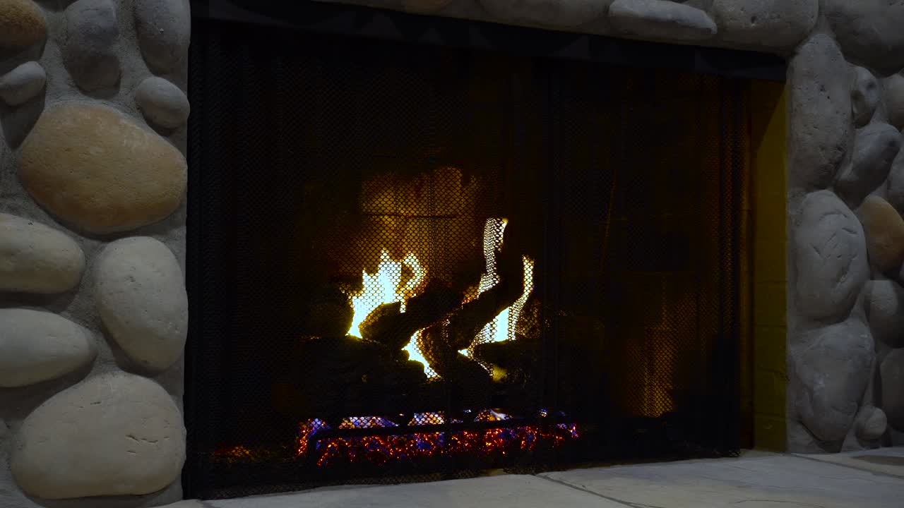 Fire burns in a fireplace at night dark romantic still shot