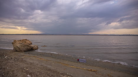 Overcast-cloudscape-over-the-Larnaca-Salt-Lake,-Cyprus-time-lapse-and-a-discarded-plastic-bottle