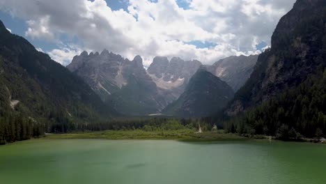 Backdrop-Aerial-of-Dolomites-in-Italy,-green-lake-and-mountain-range-at-Durrensee-,-Toblach,-Italy