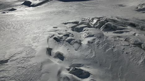 Luftaufnahme-Einer-Sonnenbeschienenen,-Verschneiten-Ebene-In-Den-Schweizer-Alpen-Im-Winter,-Kaltes-Wetter