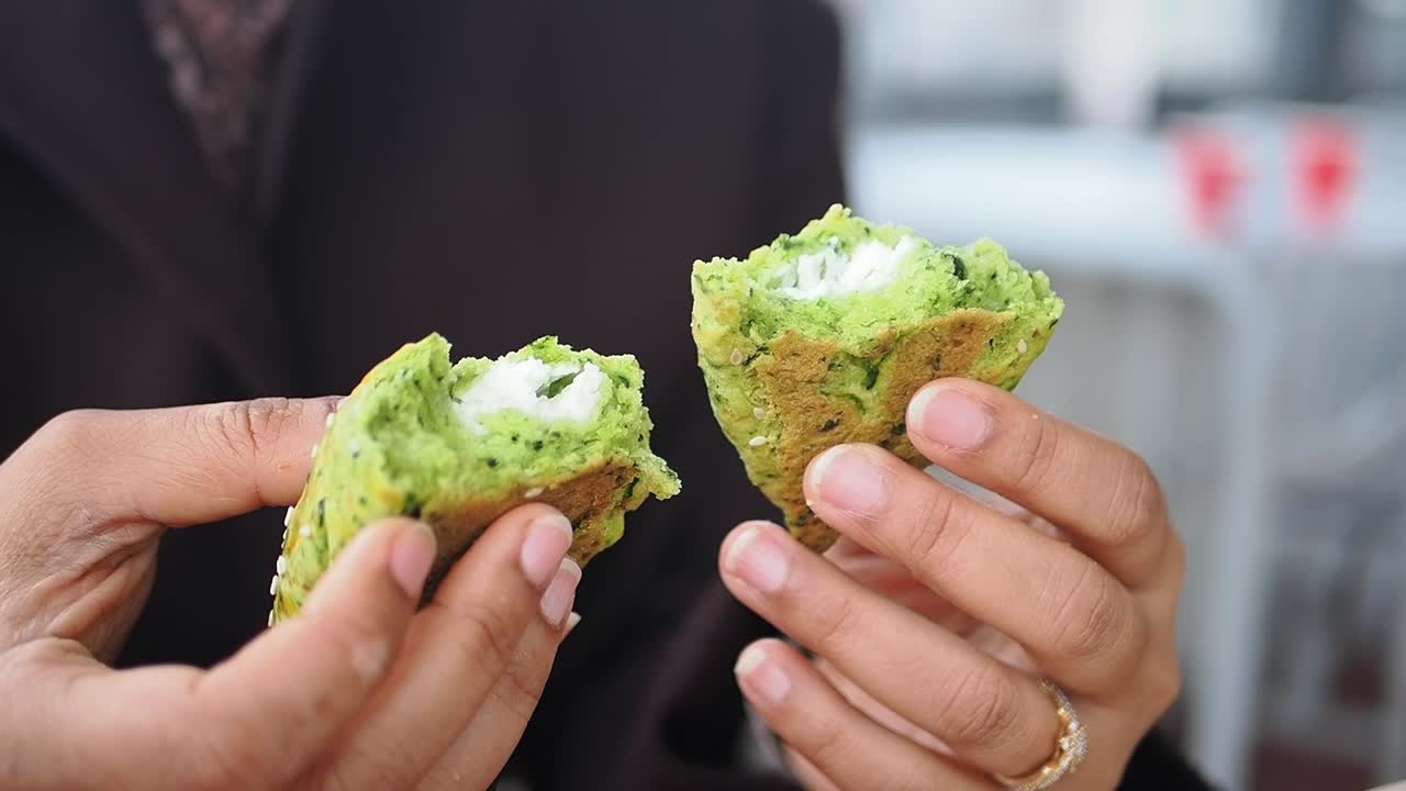 Close-up of Hands Holding Halved Green Falafel with White Filling