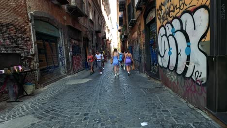 los turistas caminan por un callejón cubierto de graffiti