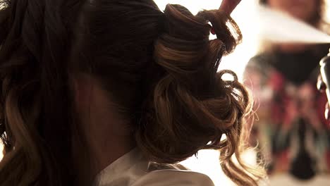 slow motion handheld shot of a hairdresser styling a bride's hair before her wedding and spraying it with hairspray