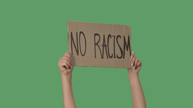Protesting poster with inscription NO RACISM. Background to illustrate the movement for the freedom of human rights. Female hands holding poster green screen, chroma key. Close up. Slow motion