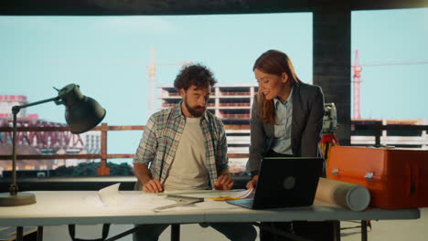 architects or engineers collaborating on blueprints at a construction site