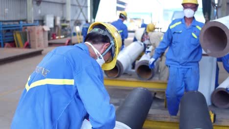 manual workers preparing fabricated steel cylindrical tubes for transporting