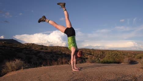 slow-motion handstand with legs splitting in the air with magnificent clouds in the background