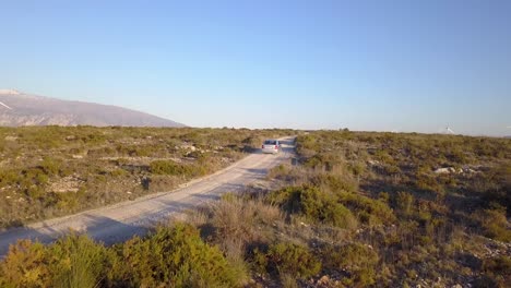 Aerial-shot-Following-an-old-car-on-a-dirt-road-in-the-countryside