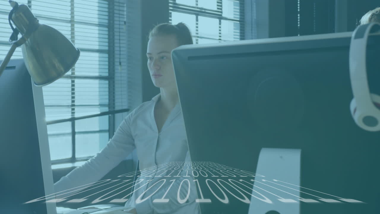 At desk, businesswoman working with binary code animation overlay, focused on task