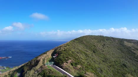 drone ascends above green trees of monte da guia revealing pico island