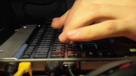 fingers typing on a laptop with a back lit keyboard