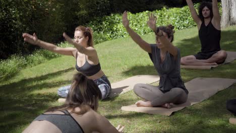 young trainer showing yoga poses in park