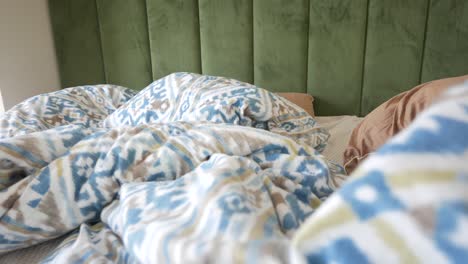 primer plano de una cama con un cabecera verde y ropa de cama con patrones
