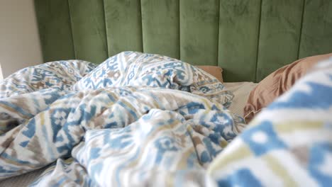 close-up of a bed with a green headboard and patterned bedding