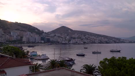 Vista-Temprano-En-La-Mañana-De-Saranda,-Albania-Con-Sol-Naciente-Lentamente-Y-Barcos-En-El-Puerto