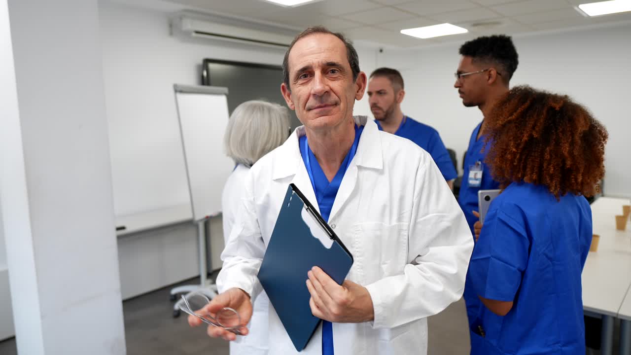 Medico anziano sorridente e sicuro di sé che tiene una cartella clinica in un ambiente ospedaliero.