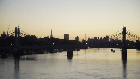 Die-Skyline-Von-London-Im-Morgengrauen-Spiegelt-Sich-In-Der-Themse-Wider,-Gesehen-Durch-Die-Albert-Bridge-Von-Der-Battersea-Bridge-Mit-Blick-Auf-Vauxhall-Und-Die-Stadt-4k