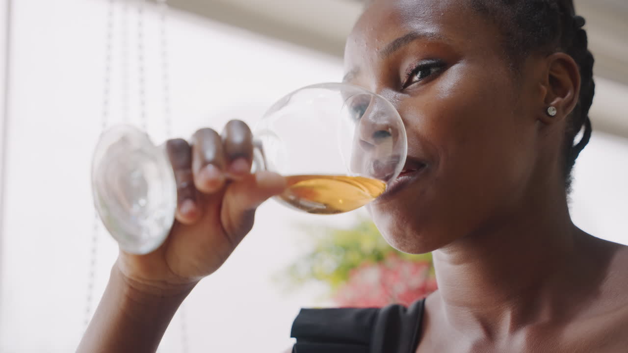 Smiling woman relishing wine at cozy cafe. Graceful woman with glass smiling on romantic city date. Refined woman drinking wine during intimate evening in lively urban cafe ambiance