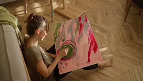 woman painting abstract art at home