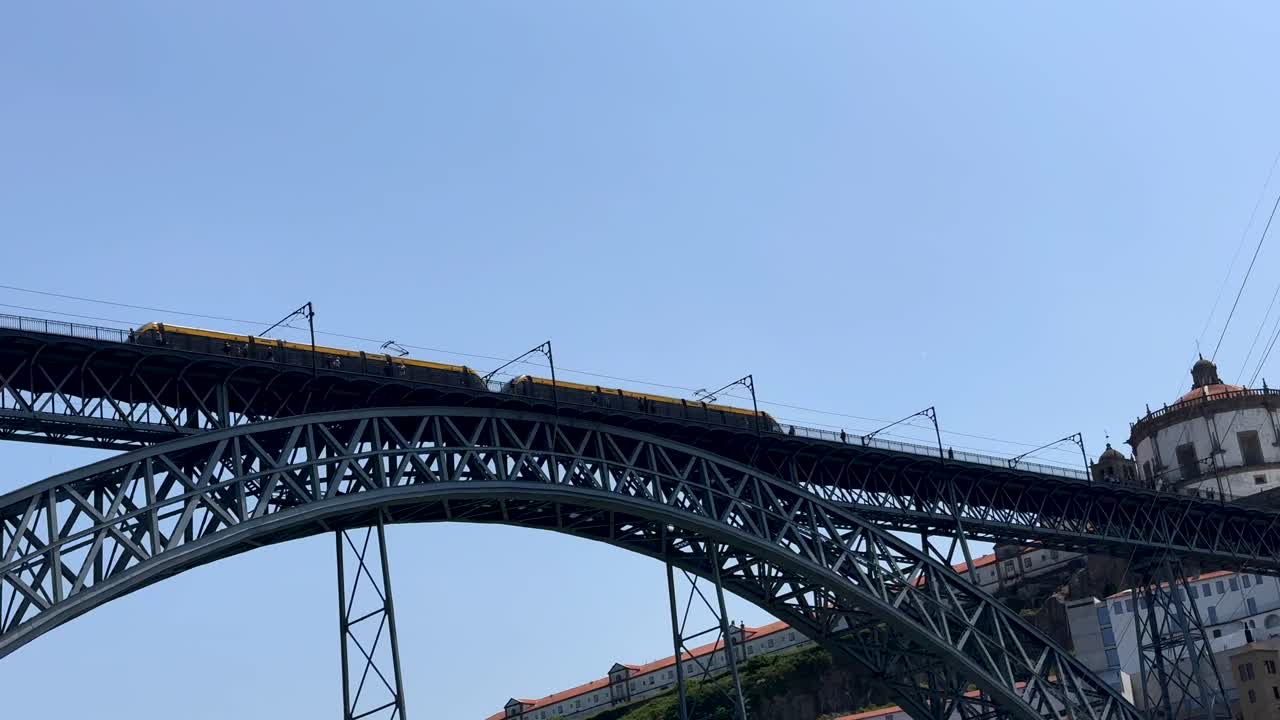Bottom up shot of riding train on top of Dom Lu&iacute;s I Bridge crossing river Douro against blue sky