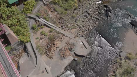 La-Panorámica-Y-La-Inclinación-Aéreas-Revelan-Una-Toma-Del-Antiguo-Puente-Peatonal-Rojo-Y-El-Río-En-La-Famosa-Ciudad-De-Onsen-De-Aguas-Termales-De-Jozankei-En-Hokkaido,-Japón