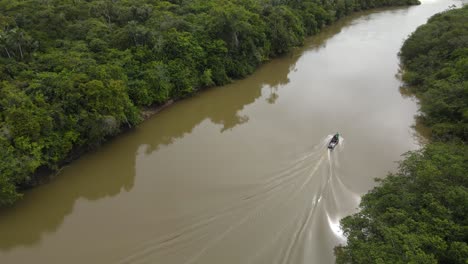 Aerial-View-of-Boat-in-Muddy-River,-Countryside-of-Guyana,-Amazon-Basin,-Drone-Shot