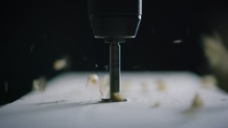 macro close up of professional carpenter working wood with drill machine in a workshop of wood factory.