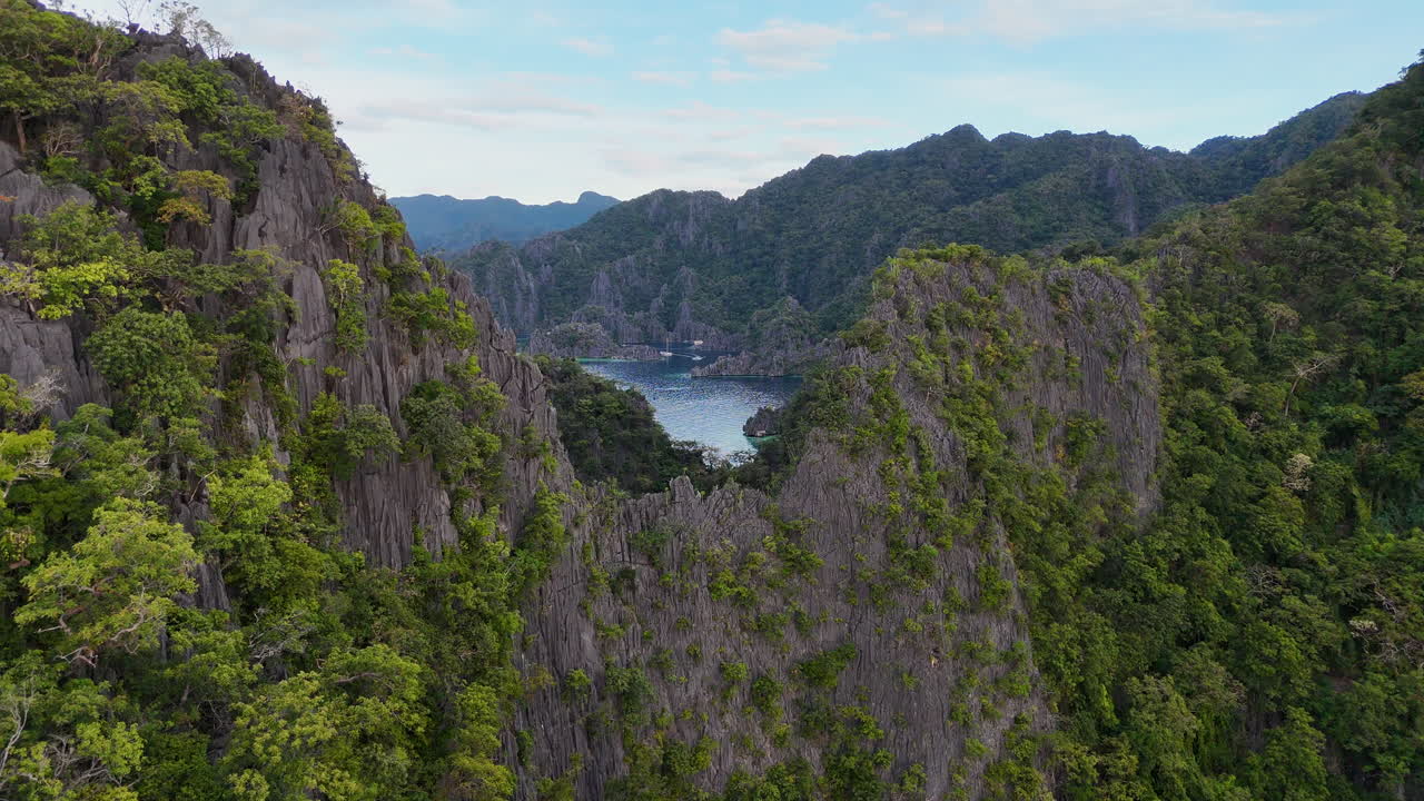 Aerial footage of Philippines Coron Island’s tropical beauty, with its dramatic cliffs, pristine beaches, and turquoise waters. With a boat in the harbor.