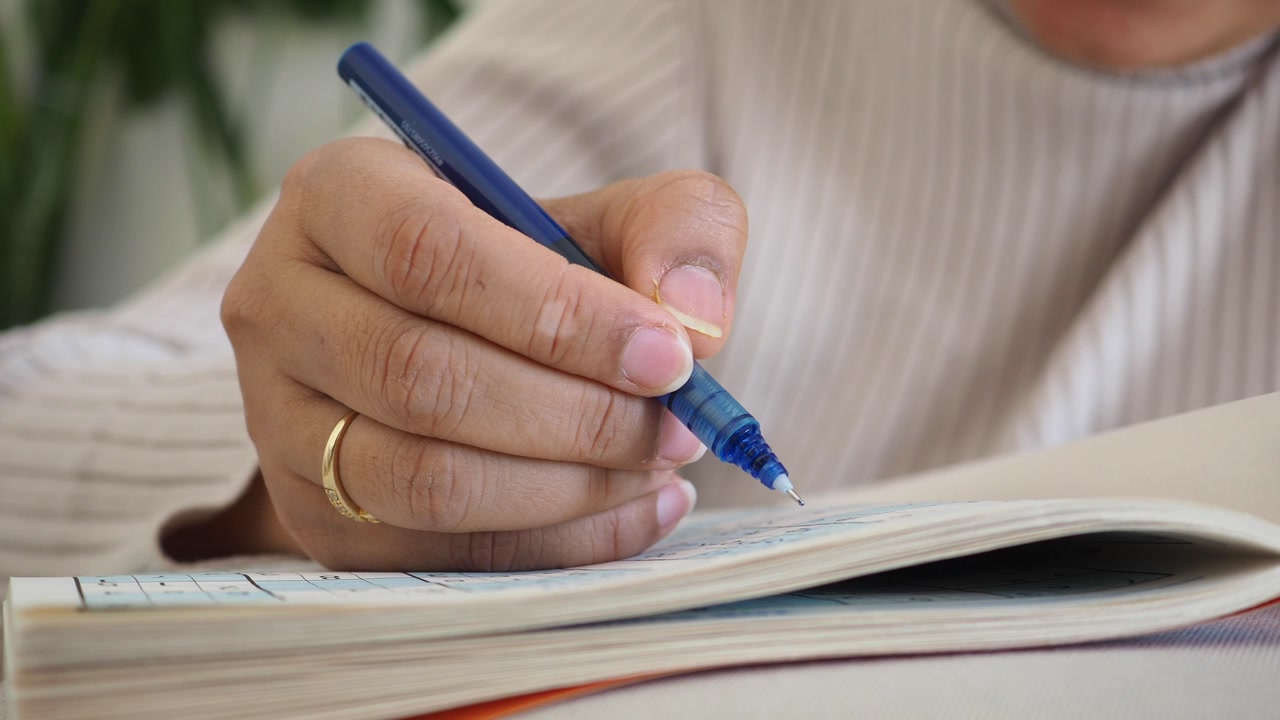 Close-up of a Hand Writing in a Notebook with a Blue Pen