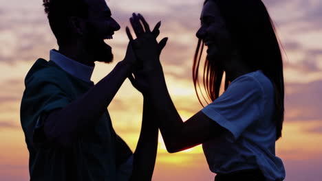 couple celebrating sunset high five