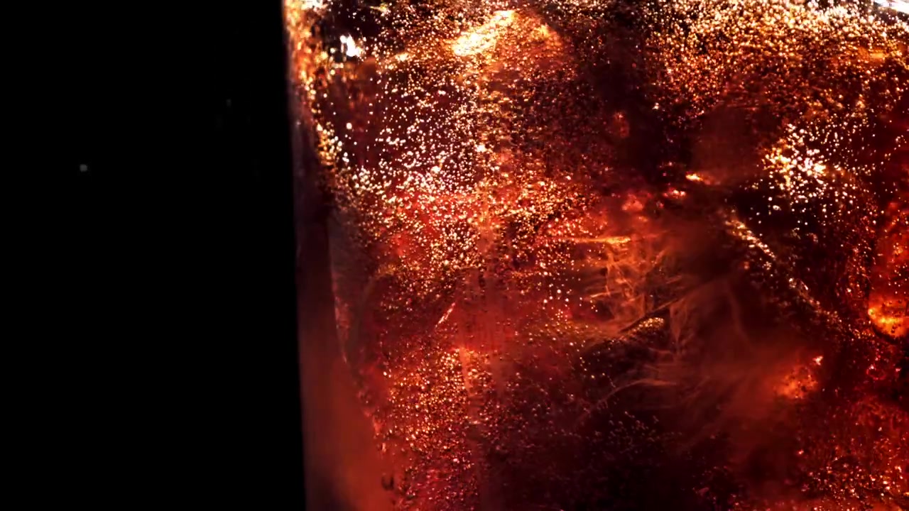Primo piano di bevanda alla cola rinfrescante con ghiaccio e bollicine