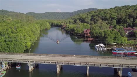 Aerial view forward following the river surrounded by lush greenery at Koh Kut Island,Thailand.A tourist boat moves towards the camera slowly along the river.
