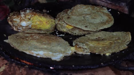 frying newari bara with eggs and meat on a skillet over a fire