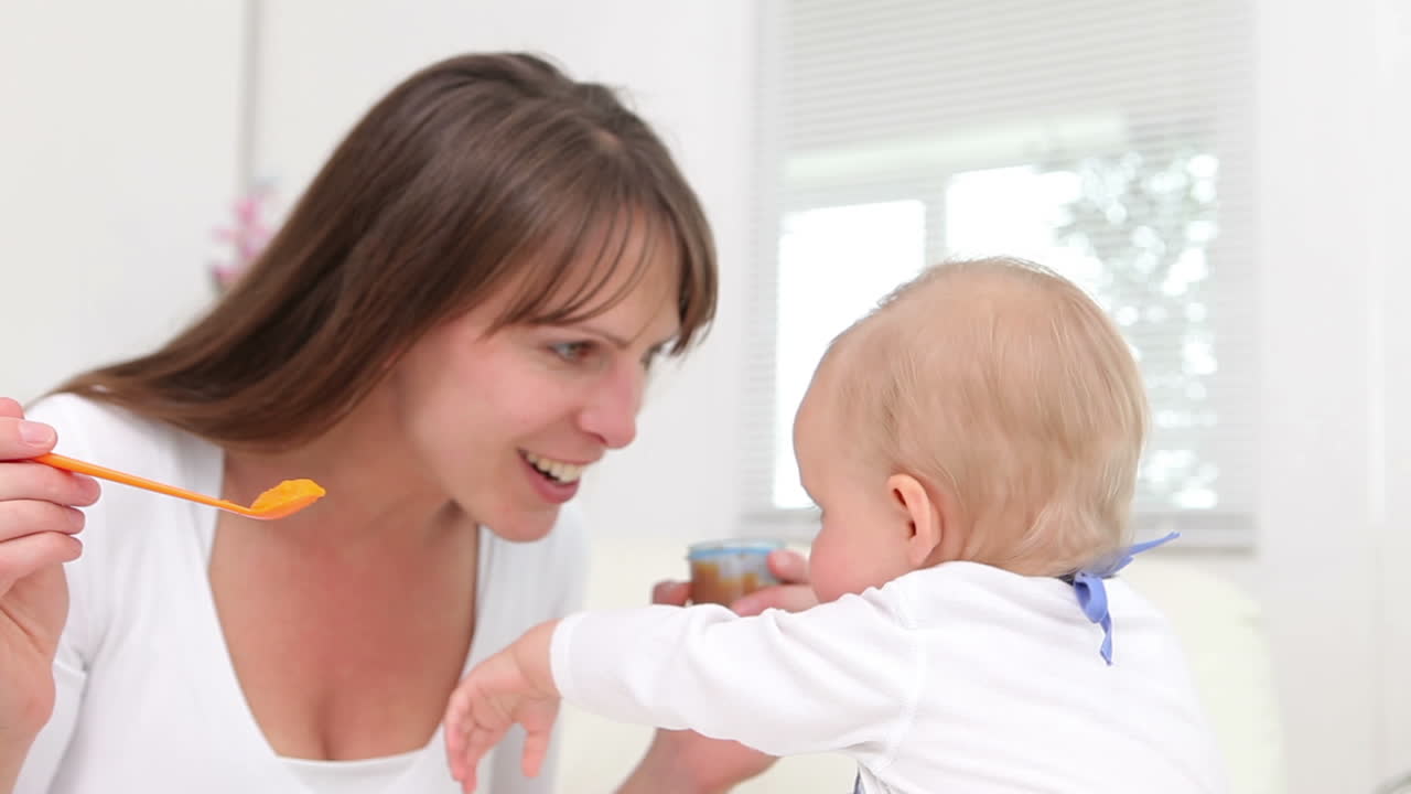 Woman feeding a baby with orange spoon