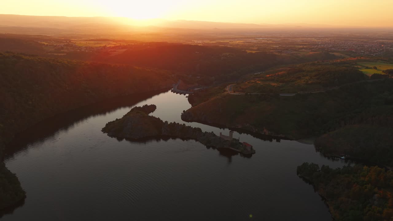 aerial shot going backward revealing the Gorges de la Loire with Grangent Island and castle in the foreground and the plain of forez in the background, loire departement, auvergne rhone alpes, france