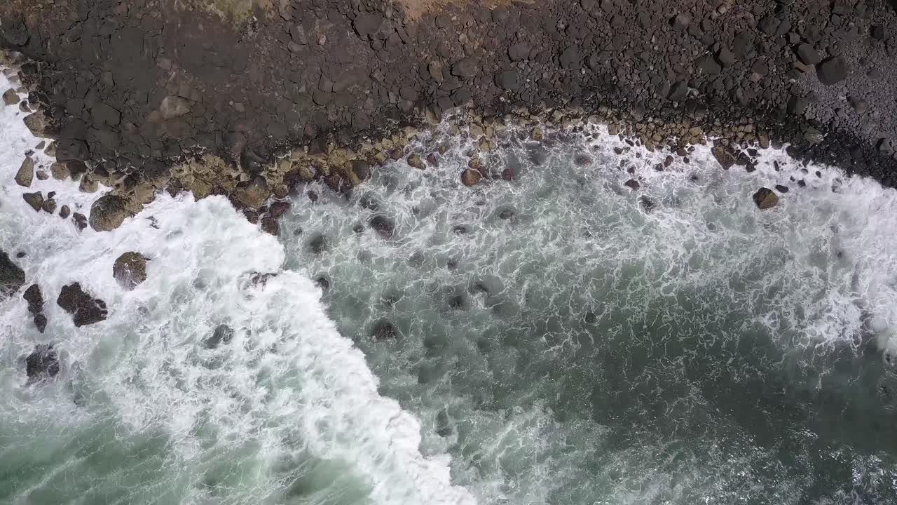 Top down view of powerful waves crashing against rocky coastline, 4k