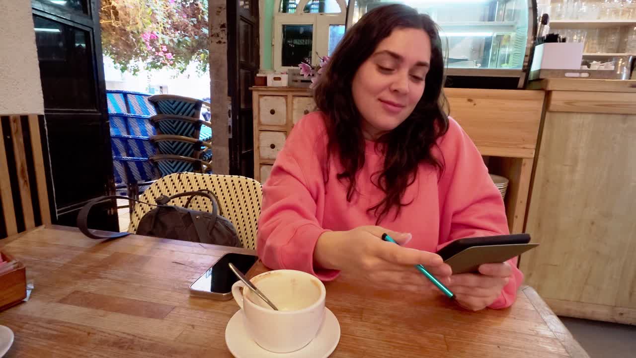 Young woman using a tablet and stylus in a cafe
