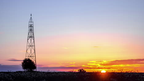 sun rising in horizon with silhouette of communication tower in foreground