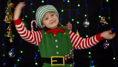 Kid-girl-in-Christmas-elf-Santa-helper-costume-dancing,-fooling-around.-New-Year-holiday-celebration